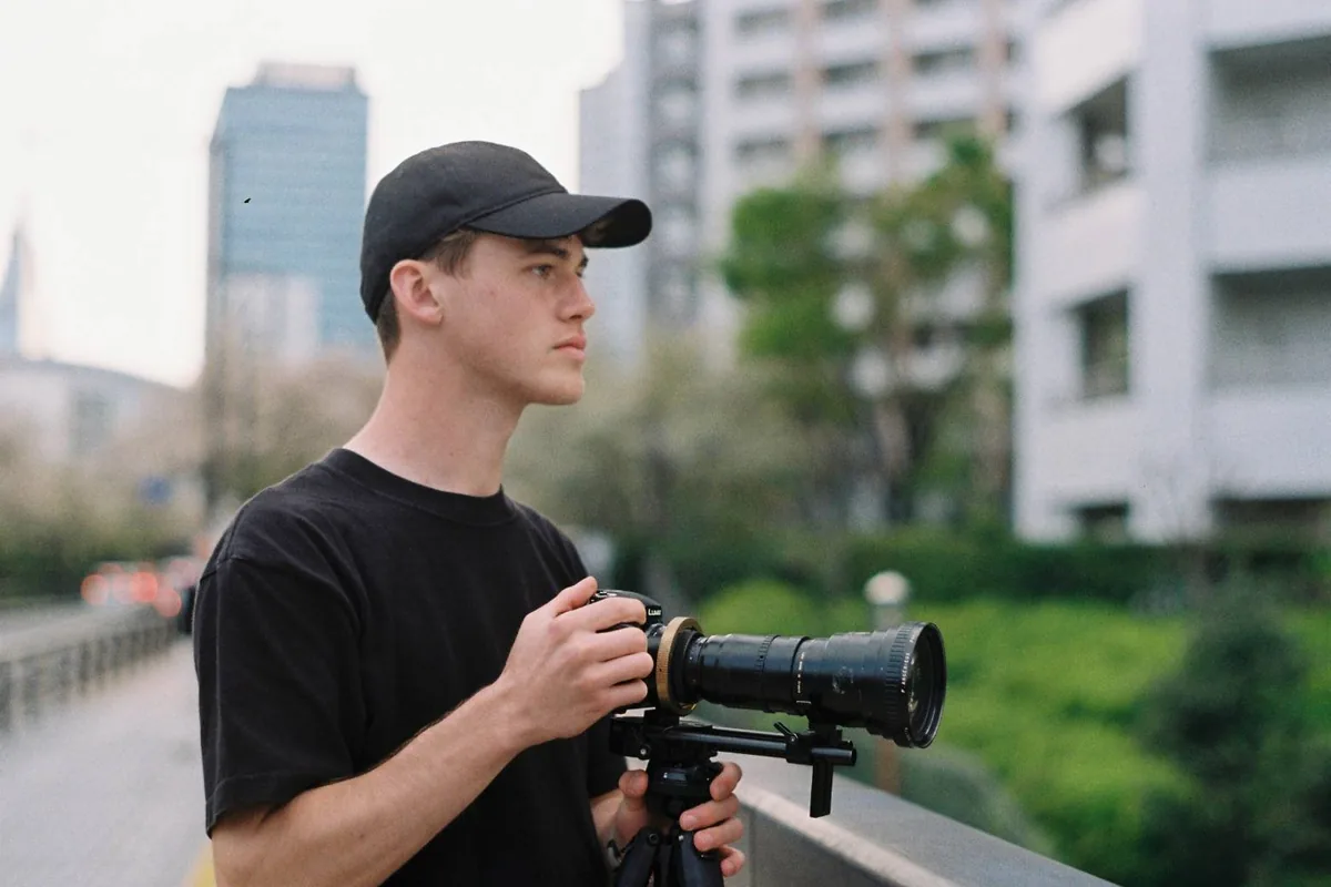 Grant Hall operating a camera rig with a long lens on a city walkway