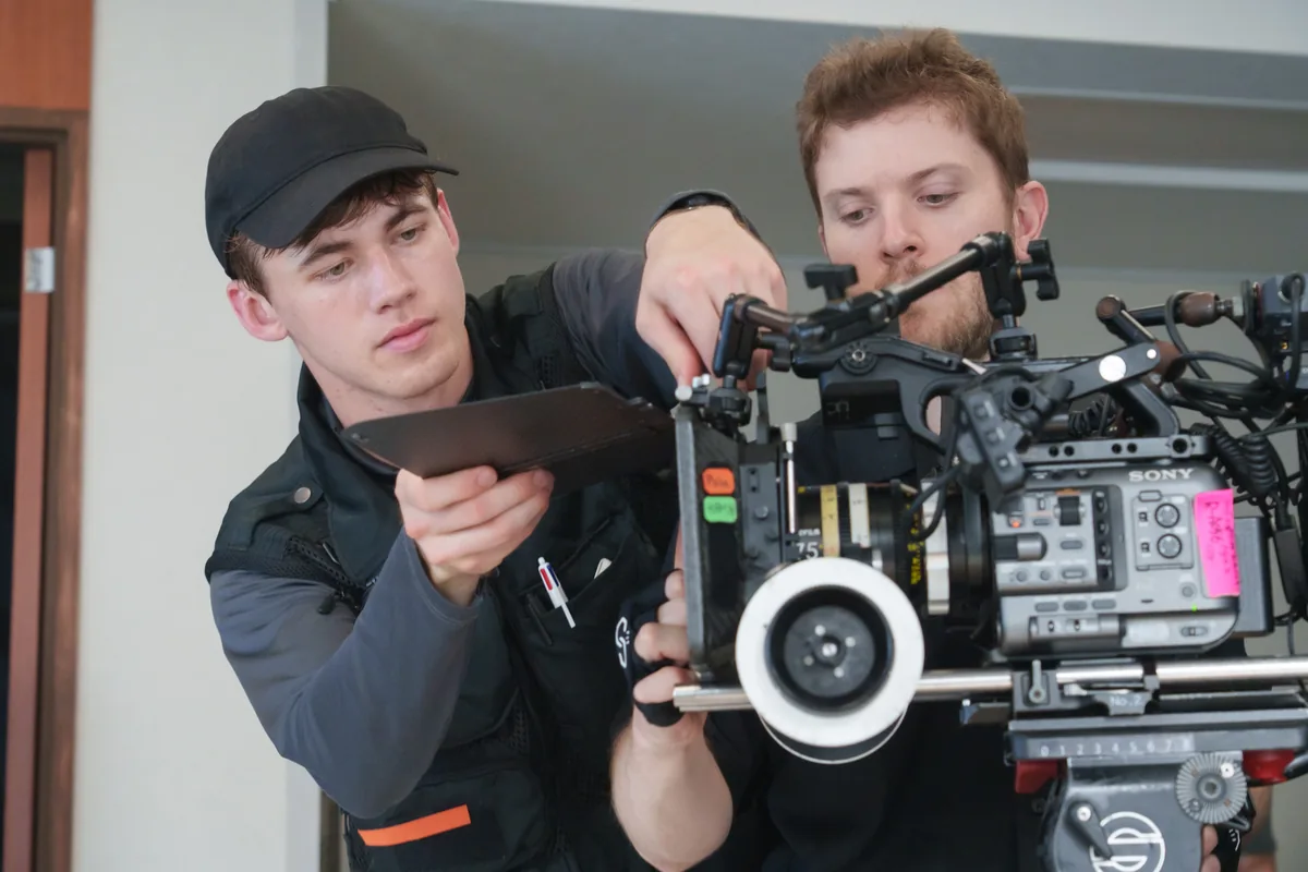 Grant Hall helping a crew member prepare a cinema camera